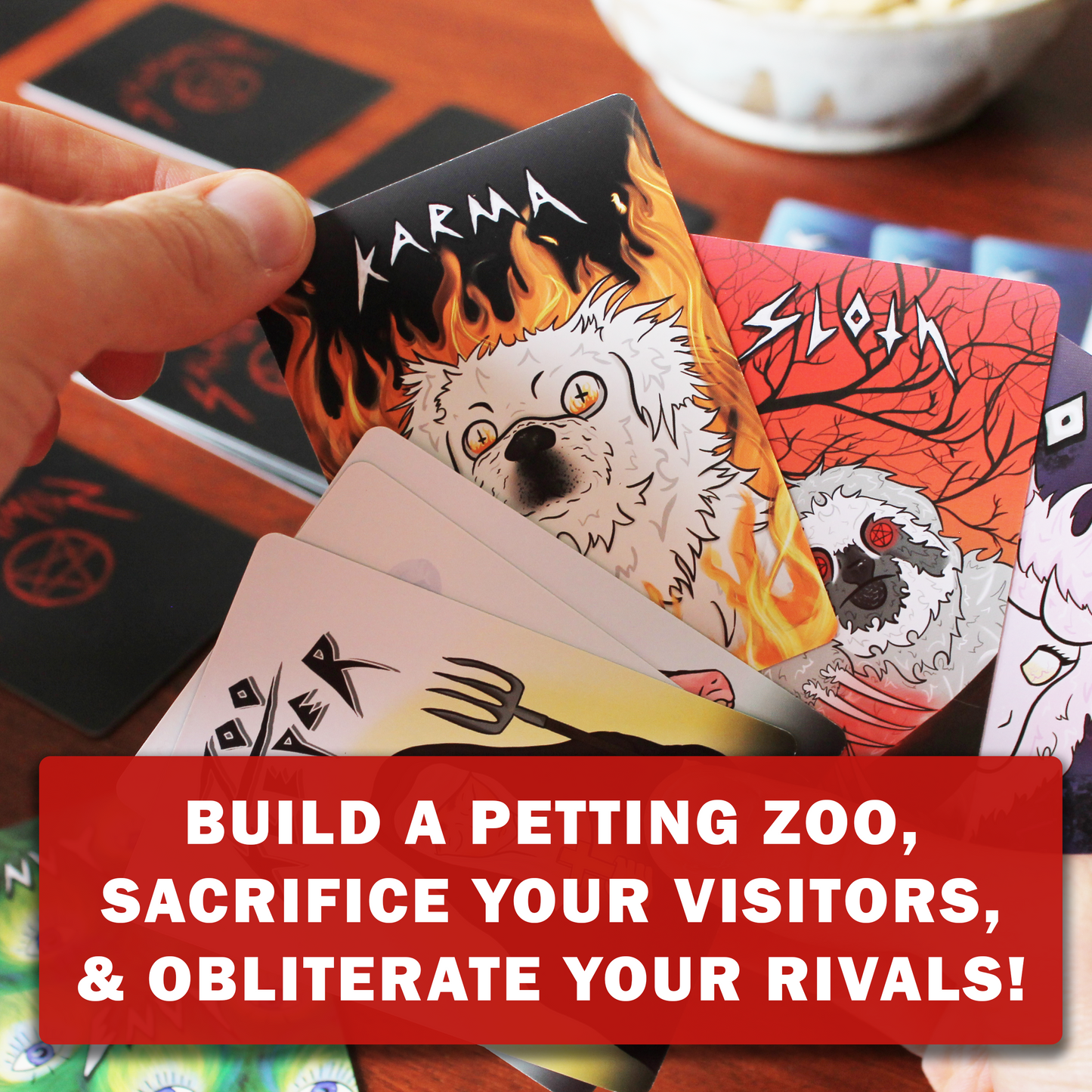 Hand holding cards with demonic animal illustrations playing SATANIMALS